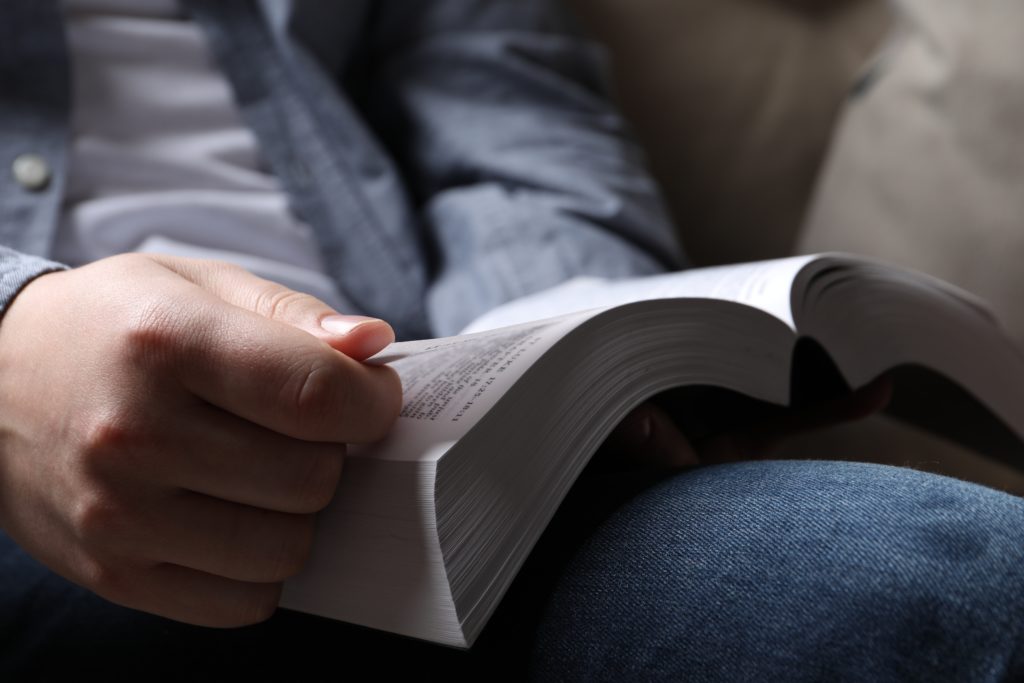 Man reading holy Bible on sofa closeup